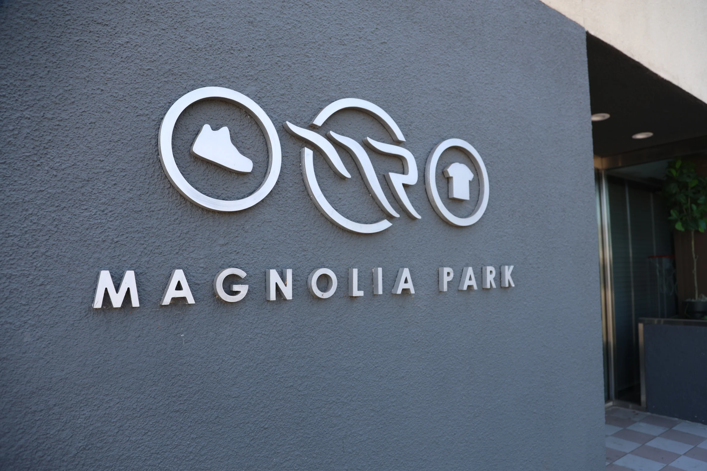 Magnolia Park sign in brushed metal letters on a gray wall